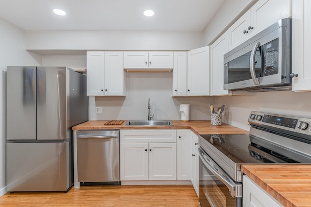 kitchen featuring appliances with stainless steel finishes, sink, white cabinets, and wood counters