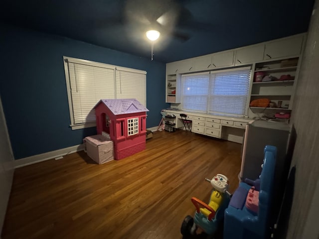 rec room with dark wood-type flooring, built in features, and ceiling fan