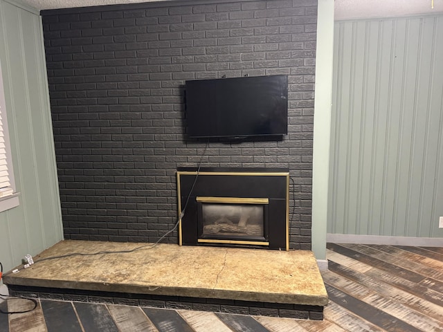 room details with a large fireplace, wooden walls, and a textured ceiling