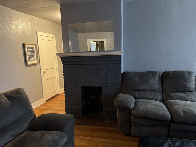 living room featuring wood-type flooring and a brick fireplace