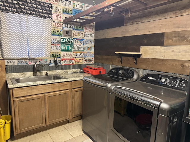 laundry room featuring sink, light tile patterned floors, washing machine and dryer, and wood walls