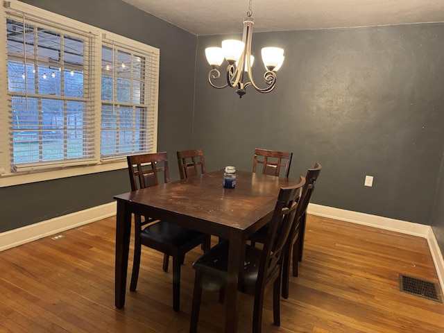 dining space featuring wood-type flooring and a notable chandelier