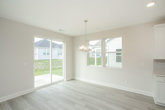 unfurnished dining area featuring light hardwood / wood-style floors and a chandelier