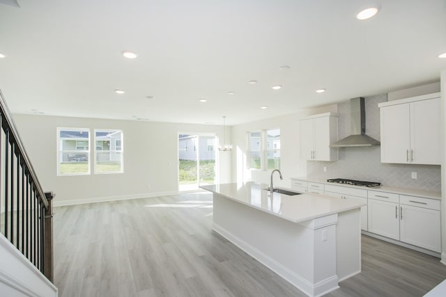 kitchen with white cabinetry, sink, a center island with sink, and wall chimney exhaust hood