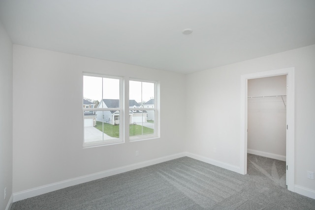 unfurnished bedroom featuring a spacious closet, carpet floors, and a closet