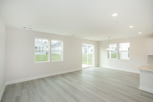 unfurnished living room featuring a chandelier and light wood-type flooring