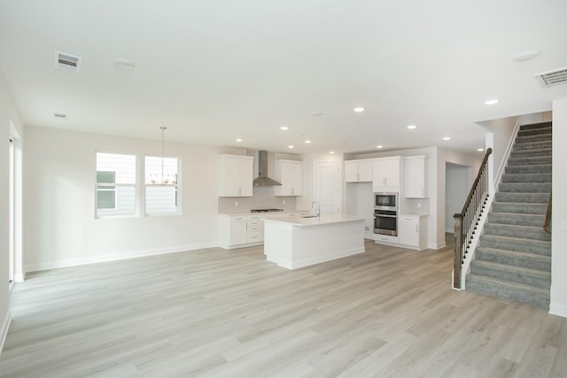 unfurnished living room featuring sink, an inviting chandelier, and light hardwood / wood-style floors