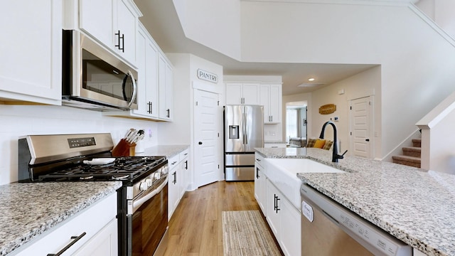 kitchen featuring light stone counters, appliances with stainless steel finishes, and white cabinets