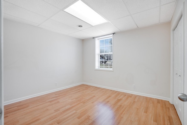 empty room with a paneled ceiling and light hardwood / wood-style flooring