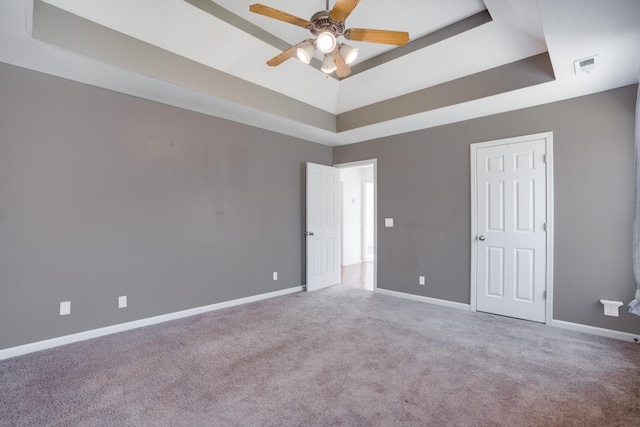 unfurnished room with ceiling fan, a tray ceiling, and carpet floors