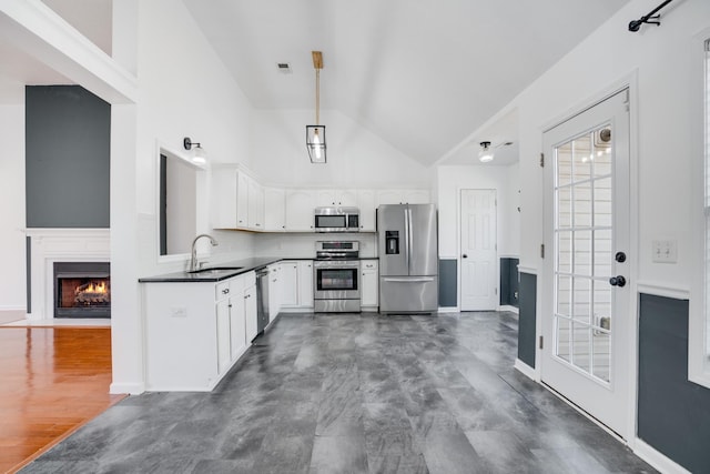 kitchen featuring high vaulted ceiling, tasteful backsplash, sink, white cabinets, and stainless steel appliances