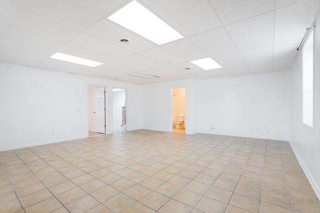 unfurnished room featuring a drop ceiling and light tile patterned floors