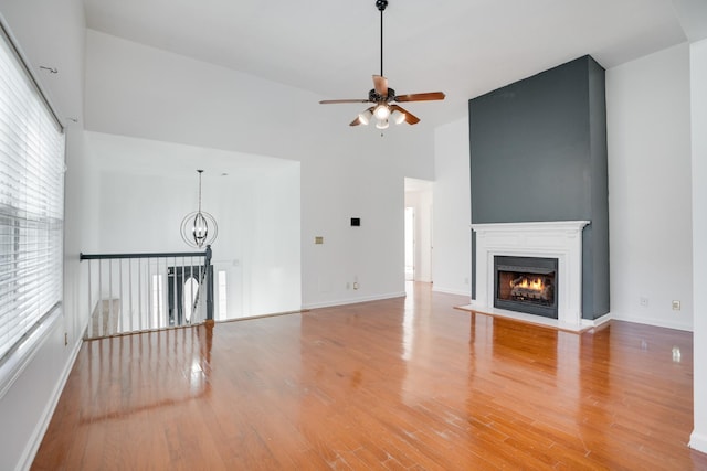 unfurnished living room with hardwood / wood-style flooring, ceiling fan with notable chandelier, and a wealth of natural light