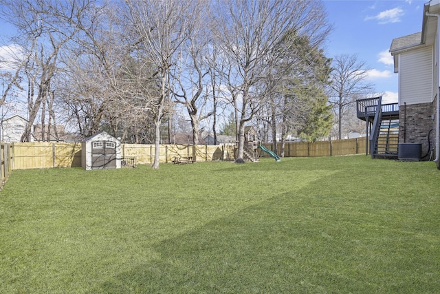 view of yard featuring a shed, central AC unit, a playground, and a wooden deck