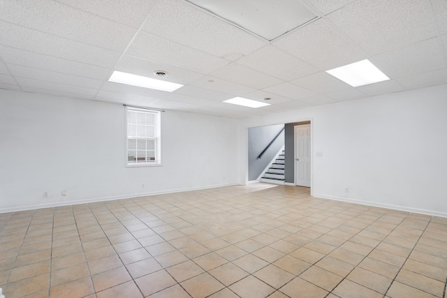 unfurnished room with a paneled ceiling and light tile patterned floors