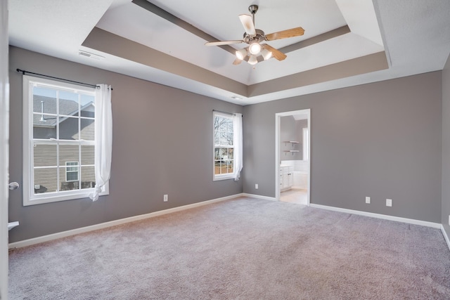 carpeted spare room featuring ceiling fan and a raised ceiling