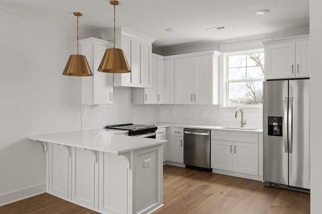 kitchen featuring decorative light fixtures, white cabinetry, sink, kitchen peninsula, and stainless steel appliances