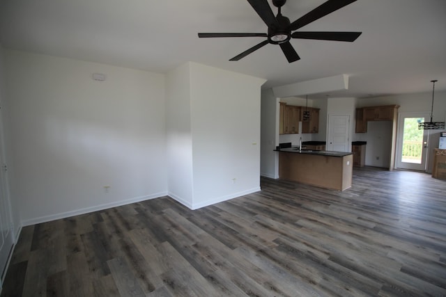 unfurnished living room featuring dark wood-type flooring, sink, and ceiling fan