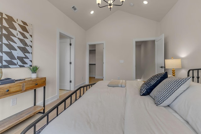 bedroom with lofted ceiling, a walk in closet, a closet, and a chandelier