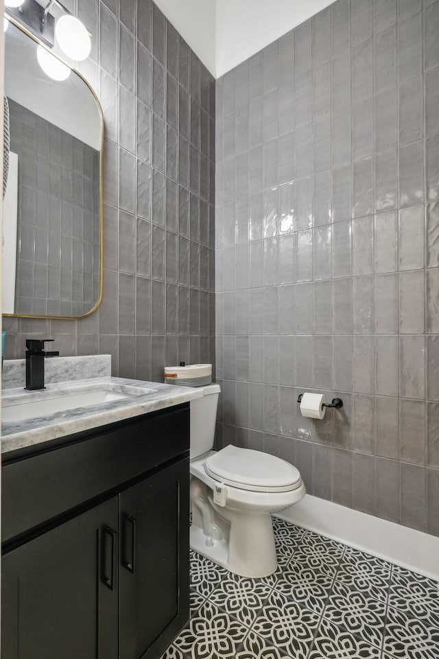 bathroom featuring vanity, tile walls, tile patterned floors, and toilet