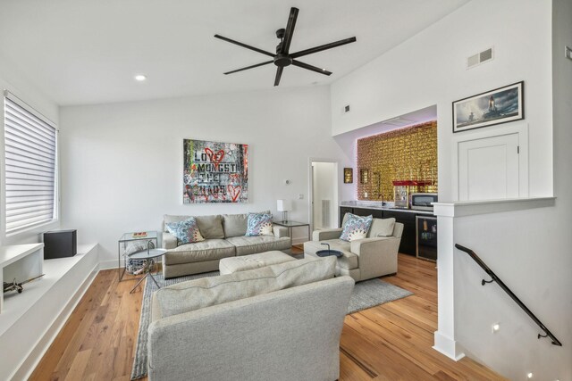 living room with wine cooler, ceiling fan, vaulted ceiling, and light hardwood / wood-style flooring