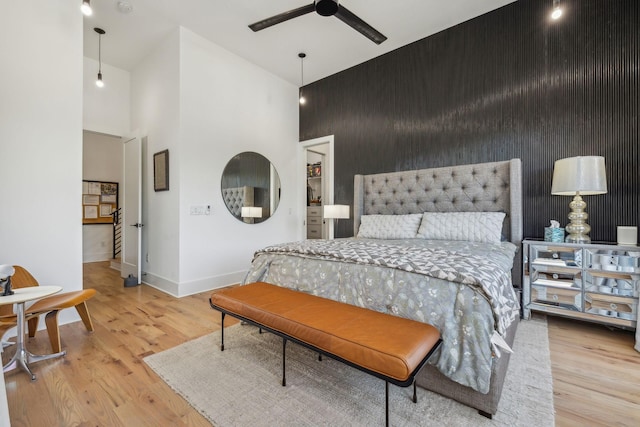 bedroom featuring a towering ceiling, ceiling fan, and light wood-type flooring