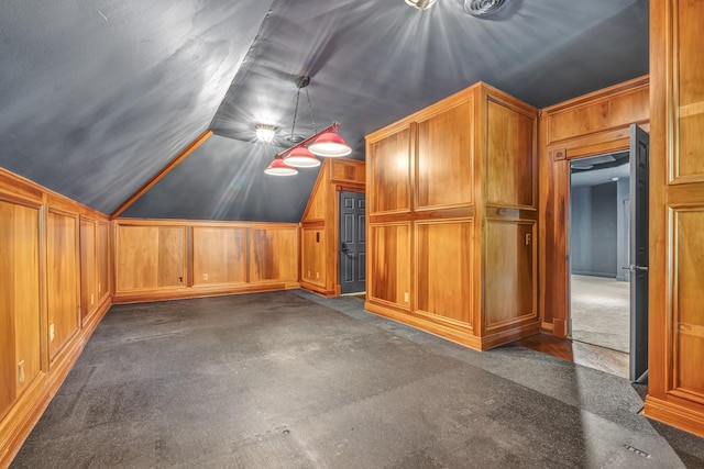 bonus room with dark colored carpet, lofted ceiling, and wooden walls