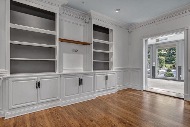 unfurnished living room with ornamental molding, dark hardwood / wood-style floors, and built in shelves