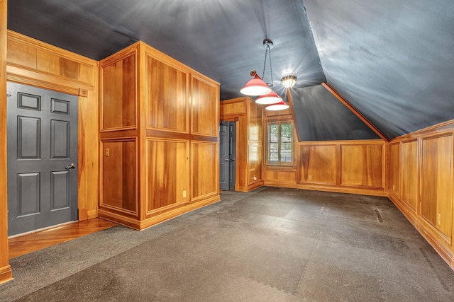 bonus room with dark carpet and vaulted ceiling