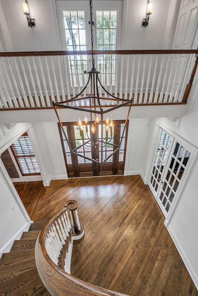 stairs with wood-type flooring and a chandelier