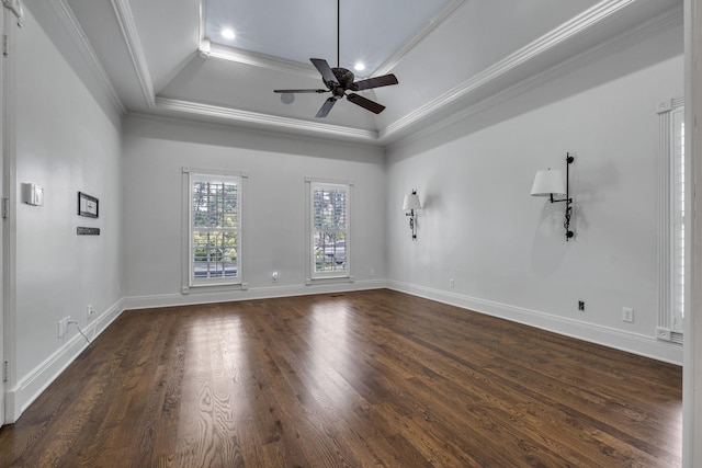 empty room with a raised ceiling, crown molding, dark hardwood / wood-style floors, and ceiling fan