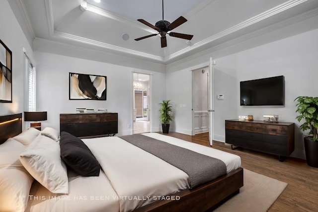 bedroom with hardwood / wood-style flooring, ceiling fan, ornamental molding, and a raised ceiling