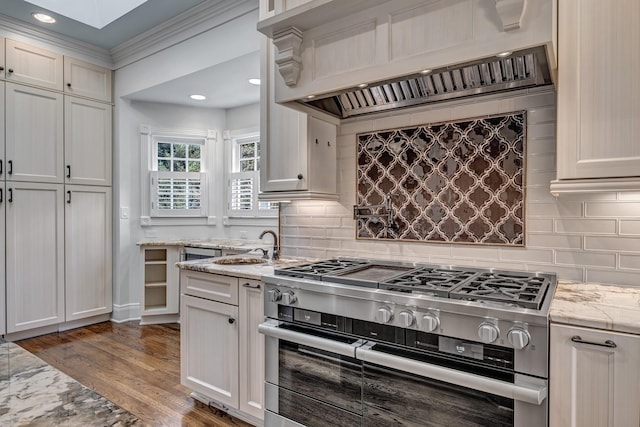 kitchen featuring premium range hood, dark wood-type flooring, tasteful backsplash, light stone countertops, and range with two ovens