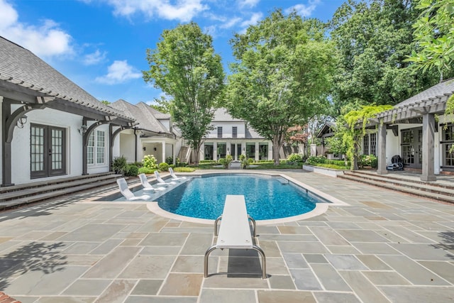 view of pool with a patio, a diving board, a pergola, and french doors