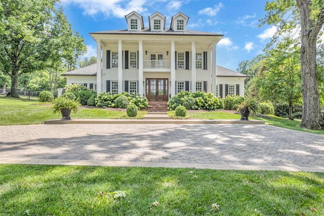 view of front facade featuring a balcony, a front yard, and french doors