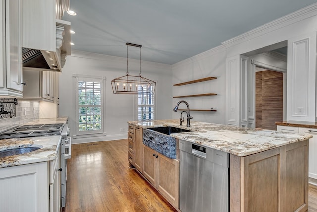 kitchen featuring sink, appliances with stainless steel finishes, a kitchen island with sink, light stone counters, and decorative light fixtures