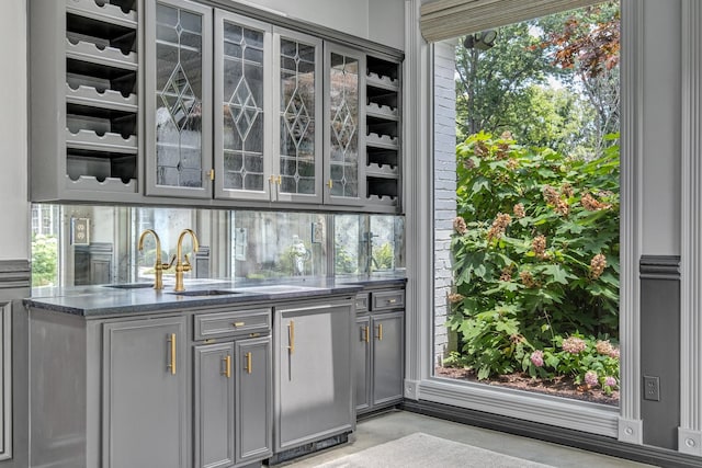 bar featuring gray cabinets, sink, and dark stone counters