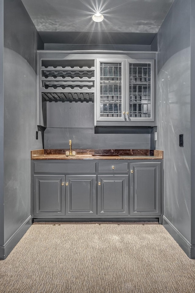 bar featuring sink, gray cabinetry, and light colored carpet