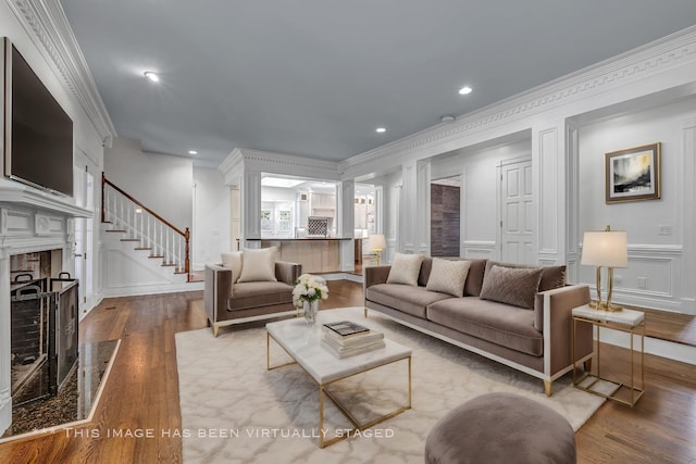 living room with wood-type flooring, ornamental molding, and a high end fireplace