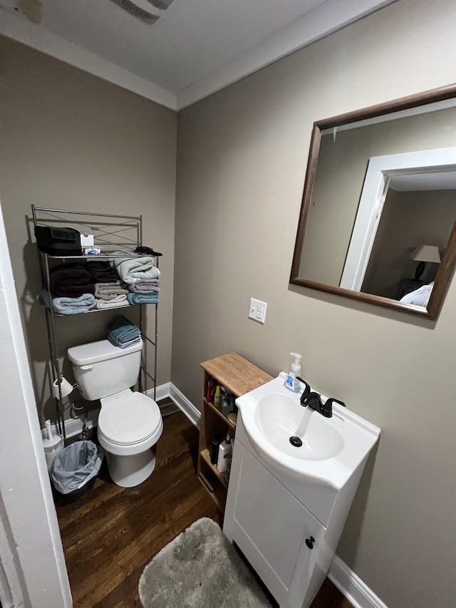 bathroom featuring vanity, hardwood / wood-style flooring, ornamental molding, and toilet