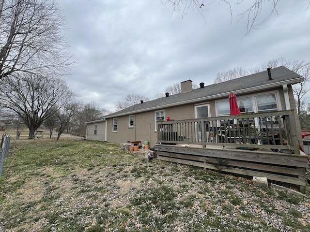 rear view of house featuring a wooden deck and a lawn