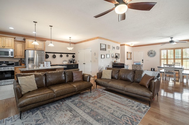 living room featuring ornamental molding, hardwood / wood-style floors, and ceiling fan