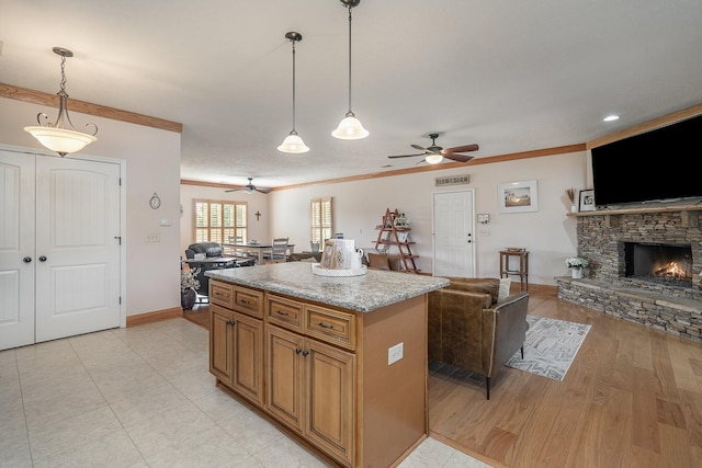 kitchen featuring ornamental molding, a kitchen island, light stone countertops, and hanging light fixtures