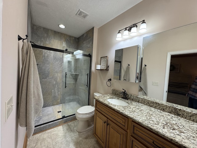 bathroom with vanity, toilet, a shower with door, and a textured ceiling