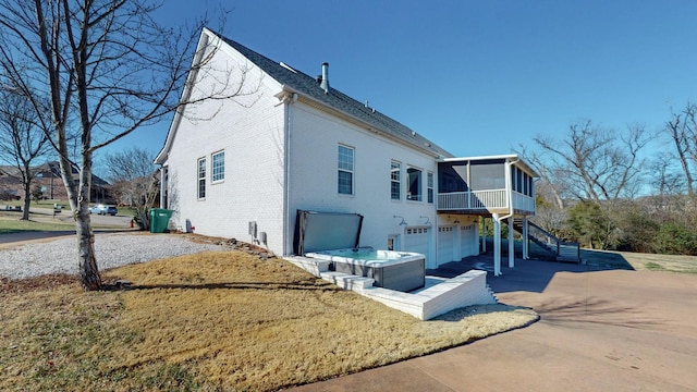 exterior space with a garage, a hot tub, and a sunroom