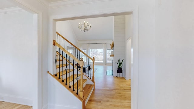 entryway with ornamental molding, a notable chandelier, and light hardwood / wood-style floors