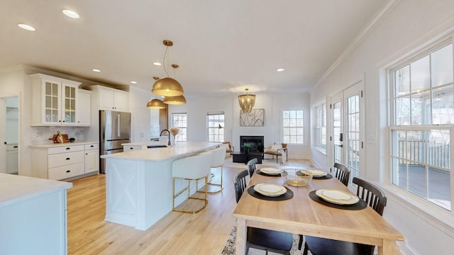 kitchen with ornamental molding, sink, hanging light fixtures, and white cabinets