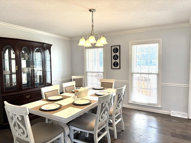 dining space featuring ornamental molding, dark hardwood / wood-style flooring, a textured ceiling, and a notable chandelier