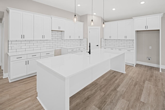 kitchen with white cabinetry and an island with sink