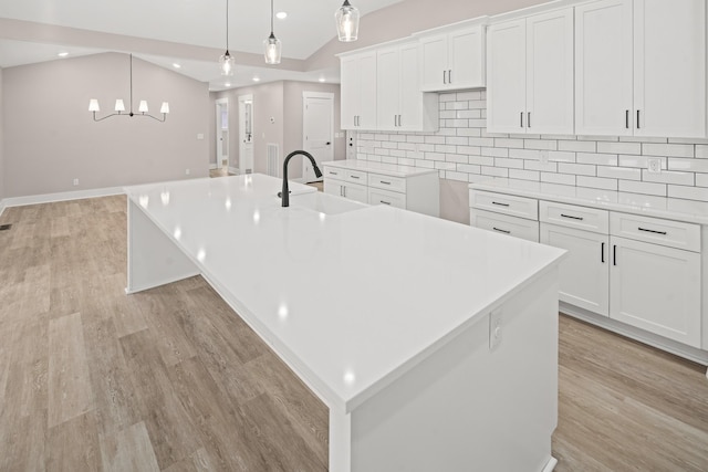 kitchen featuring lofted ceiling, sink, a spacious island, white cabinets, and decorative light fixtures